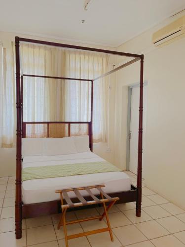 a bedroom with a canopy bed with a wooden frame at Bungles Ungalow in Castries