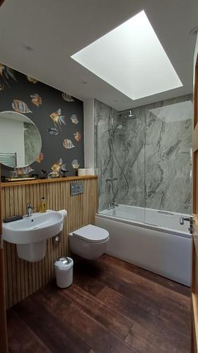 a bathroom with a sink and a tub and a toilet at Cottages Lyndale Farm in Flashader