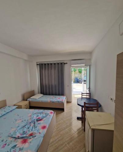 a hotel room with two beds and a table and a room at Renato Rooms & Apartments in Vlorë