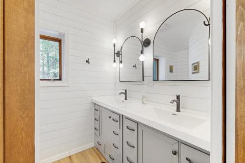 a white bathroom with two sinks and a mirror at Beebe Lake House in Castleton