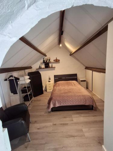 a attic bedroom with a bed and a chair at B&B Pied à Pieter in Maastricht
