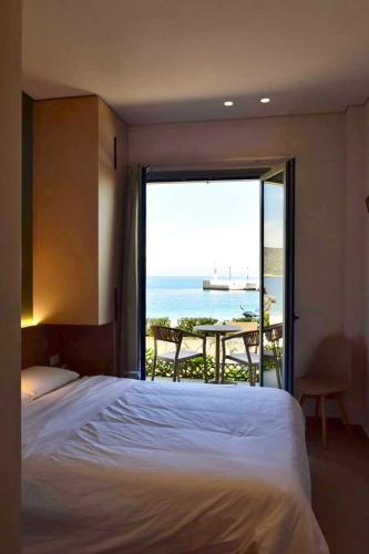 a bedroom with a bed and a view of the ocean at Okeanis Hotel Tyros in Tyros