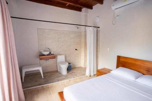 a bedroom with a white bed and a toilet at Casa Manglares Capurganá in Acanti