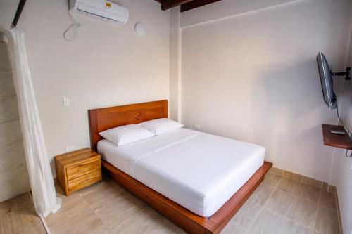 a bedroom with a white bed and a wooden headboard at Casa Manglares Capurganá in Acanti