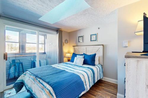 a bedroom with a bed with blue sheets and a window at Splash & Relax Unit 203 in Wells