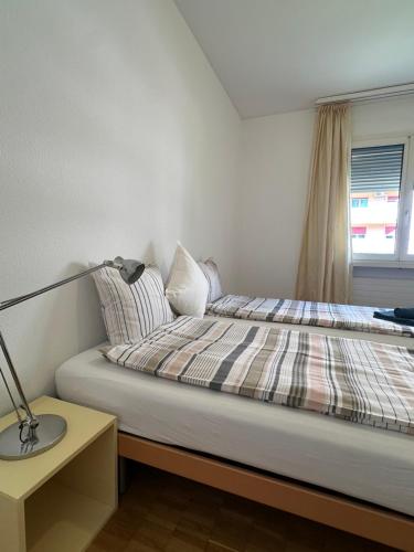 a bedroom with a bed with a lamp and a window at QuietApartment in Bellinzona