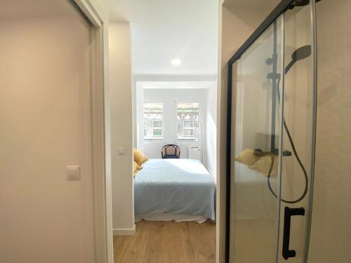 a bedroom with a white bed and a glass door at El Patio de María in Ferrol