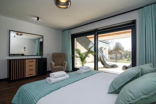 a bedroom with a large bed with a large window at Slotvin Apartments in Słotwiny