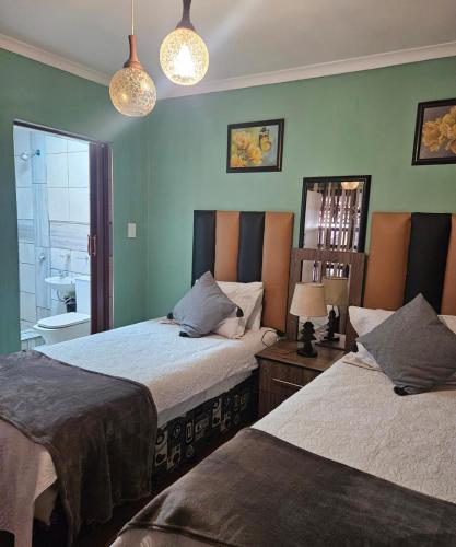 two beds in a room with green walls at Orca Estate Guesthouse Self-catering Accommodation in Durban