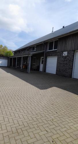 a building with white garage doors and a brick driveway at Franzenhof Beldorf in Beldorf