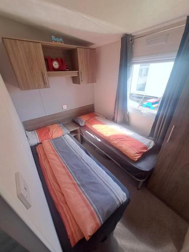 a small room with two beds and a window at Trecco Bay Cwtch Caravan in Newton