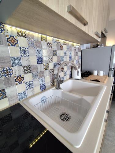 a white sink in a kitchen with tiles at BlueHouse III in Palekastron