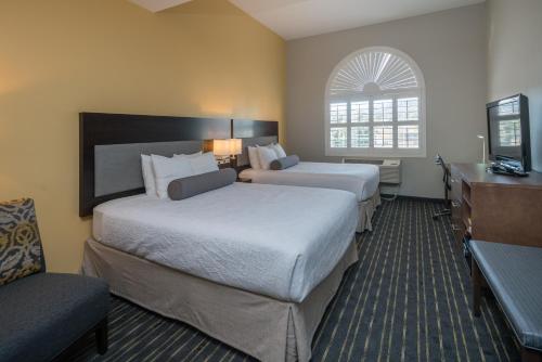 a hotel room with two beds and a television at Hotel Aura SFO Airport in San Bruno