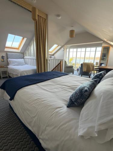 a large white bed in a room with windows at Y Stabl in New Quay