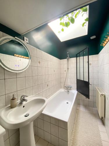 a bathroom with a sink and a tub and a mirror at Maison Basse in Malestroit