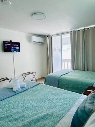 a hotel room with two beds and a balcony at Verano Azul Beachfront Apartment in Isabela in Isabela