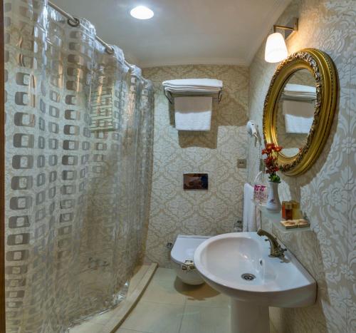 a bathroom with a sink and a mirror and a toilet at By Murat Royal Hotel Galata in Istanbul