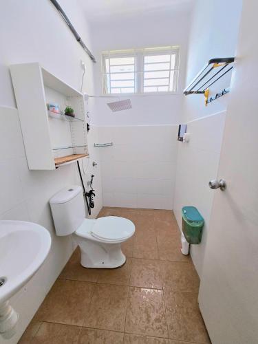 a white bathroom with a toilet and a sink at Homestay DAR AL - JUFRY fully aircond in Kuantan