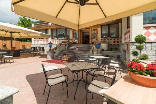 a patio with tables and chairs and an umbrella at Hotel Bellavista in Pinzolo