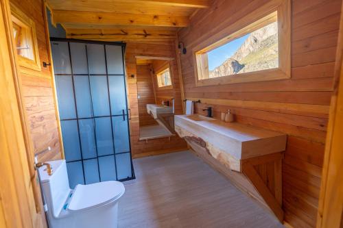 a bathroom with a toilet and a sink and a window at Bonanza Glamp Nature Experience in El Chalten