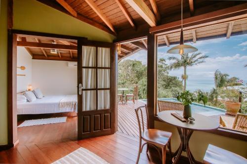 a room with a bed and a table and a balcony at Pousada Caminho do Rei in Praia do Rosa