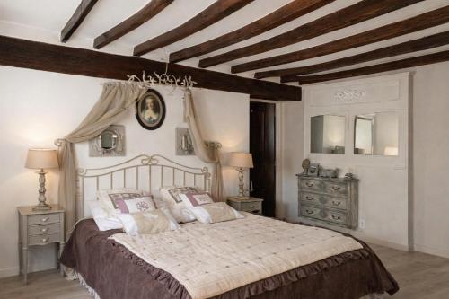 a bedroom with a large bed and wooden ceilings at Chic et Charme Cottage in Suzay