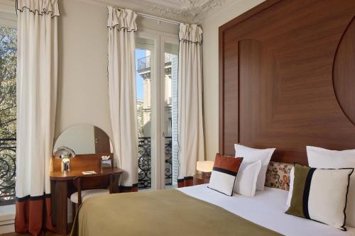 una camera da letto con un letto, una scrivania e una finestra di Hôtel d'Argenson a Parigi