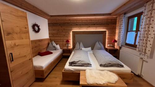 two beds in a room with wooden walls at Biobauernhof Windbachgut in Eben im Pongau