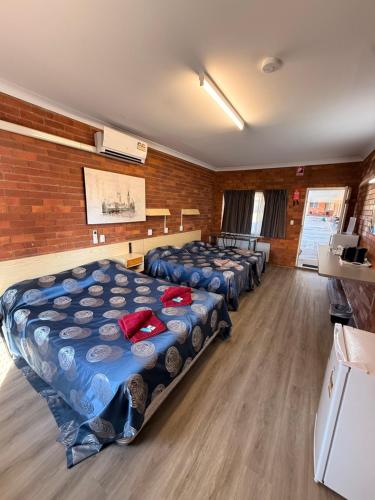 a room with four beds in a row in a room at Glen Innes Lodge Motel in Glen Innes