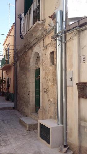 a stone building with a green door and a window at Parva Domus Intera casa indipendente in centro in Modica
