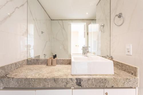 a white bathroom with a sink and a mirror at Studio completo estilo casa com lava e seca, Go Inn in Brasília