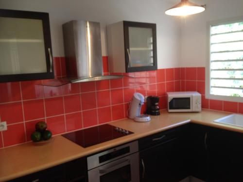 a red tiled kitchen with a sink and a microwave at Eden Blue in Sainte-Anne