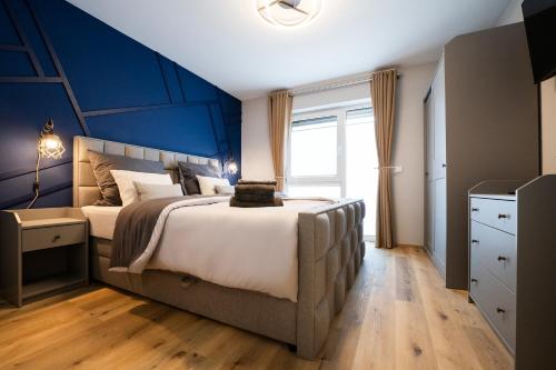 a bedroom with a large bed with a blue accent wall at Ferienwohnung RaiKa in Moers