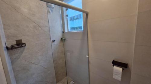 a shower with a glass door in a bathroom at Suíte Individual, ampla, aconchegante e com 2 ventiladores! in Vitória