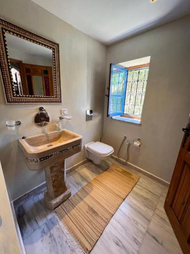 a bathroom with a sink and a toilet and a mirror at Houch Ennejma, Chambres d'hotes, Spa et bien être in Al Ḩārah al Kabīrah