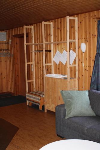 a living room with a couch and wooden walls at Comfortable and cozy cottage in Sysslebäck