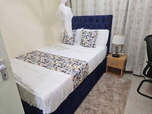 a bedroom with a bed with a blue headboard at Favoured Guest House in Nairobi
