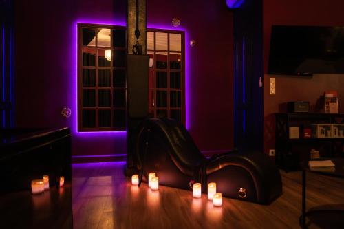 a living room with purple lighting and a chair with candles at Suite romantique avec Balneo et jeux coquins in Roanne