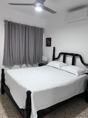 a bedroom with a black and white bed with a ceiling fan at Bijoc 01 Apartment in San Felipe de Puerto Plata