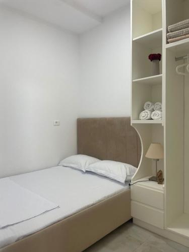 a bedroom with a bed and a shelf with towels at Santorini Drimadh Apartment in Gjilek