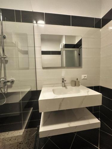 a bathroom with a white sink and a mirror at DuoNest Gray Loft Studio in Tirana