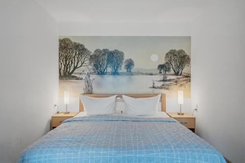 a bedroom with a blue bed with a painting on the wall at Berolina C 106 in Dahme