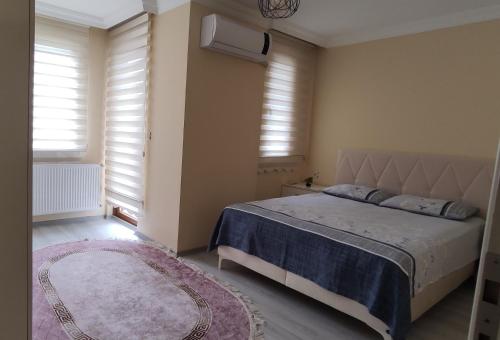 a bedroom with a bed and a rug and windows at Bıyıklı House in Akcaabat