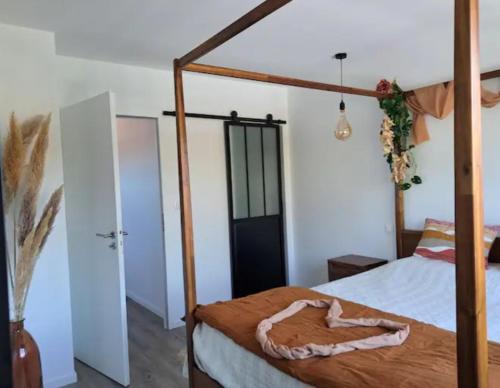 a bedroom with a canopy bed with a wooden frame at Location maison confortable et cozi in Cazaux