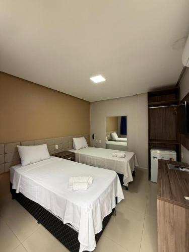 a hotel room with two beds with white sheets at Hotel Antiga Roma in Belém