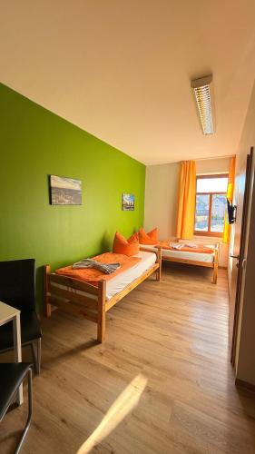 a room with two beds and a green wall at Wurzelrudis Hostel in Eibenstock