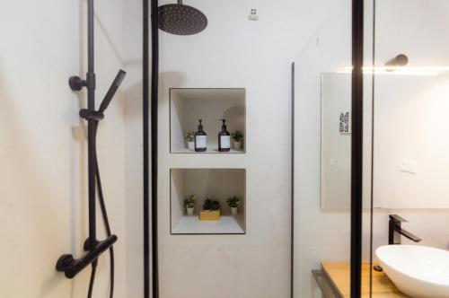 a bathroom with a glass door with bottles on shelves at Apartamentos Turísticos Penadés in Tomelloso