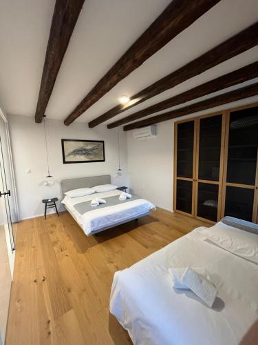two beds in a room with wooden floors at Hiša Marija Private Spa Villa in Zgornje Škofije