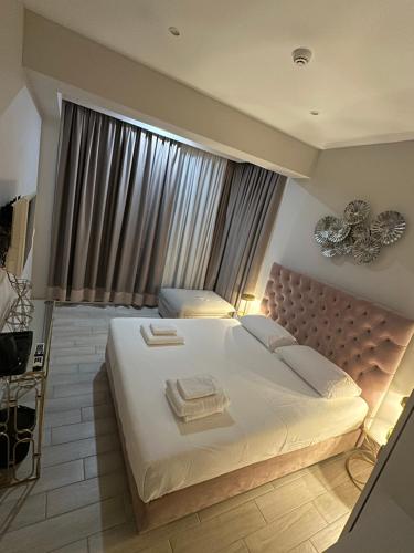 a bedroom with a large white bed with a large window at Ajsel Luxury Rooms in Sarandë