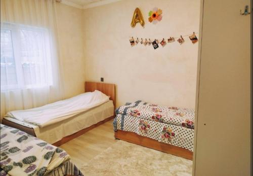 a bedroom with two beds and a alphabet on the wall at happy star stay in Sheki